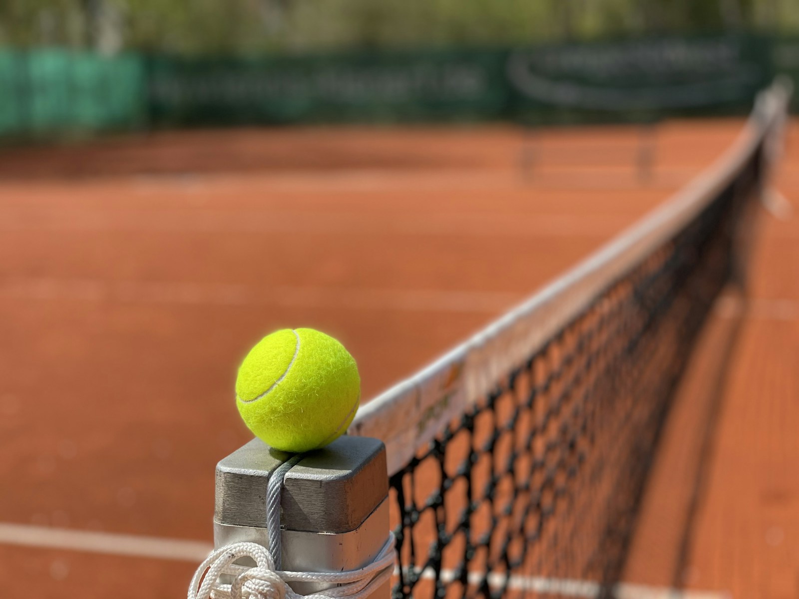 Tennisball am Netz eines Sandplatzes